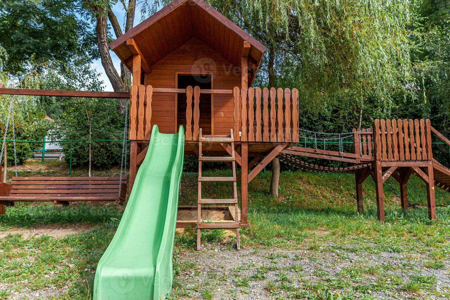 Empty modern wooden children playground set on green yard in public park in summer day. Funny toy land for kids. Urban exercise activities for child outdoors. Neighborhood childhood concept. photo