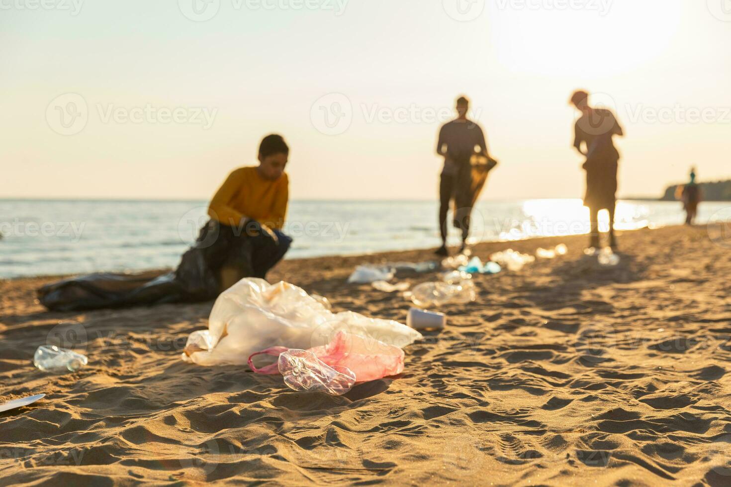 Earth day. Volunteers activists collects garbage cleaning of beach coastal zone. Woman and mans puts plastic trash in garbage bag on ocean shore. Environmental conservation coastal zone cleaning. photo