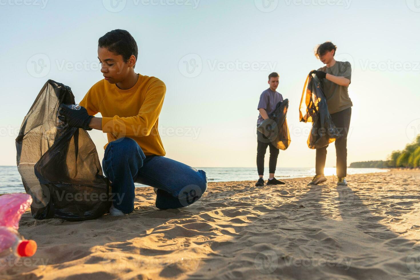 Earth day. Volunteers activists collects garbage cleaning of beach coastal zone. Woman and mans puts plastic trash in garbage bag on ocean shore. Environmental conservation coastal zone cleaning. photo