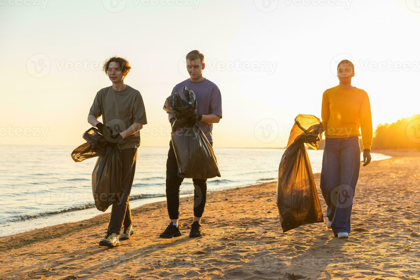 Earth day. Volunteers activists collects garbage cleaning of beach coastal zone. Woman mans with trash in garbage bag on ocean shore. Environmental conservation coastal zone cleaning. Blurred video. photo