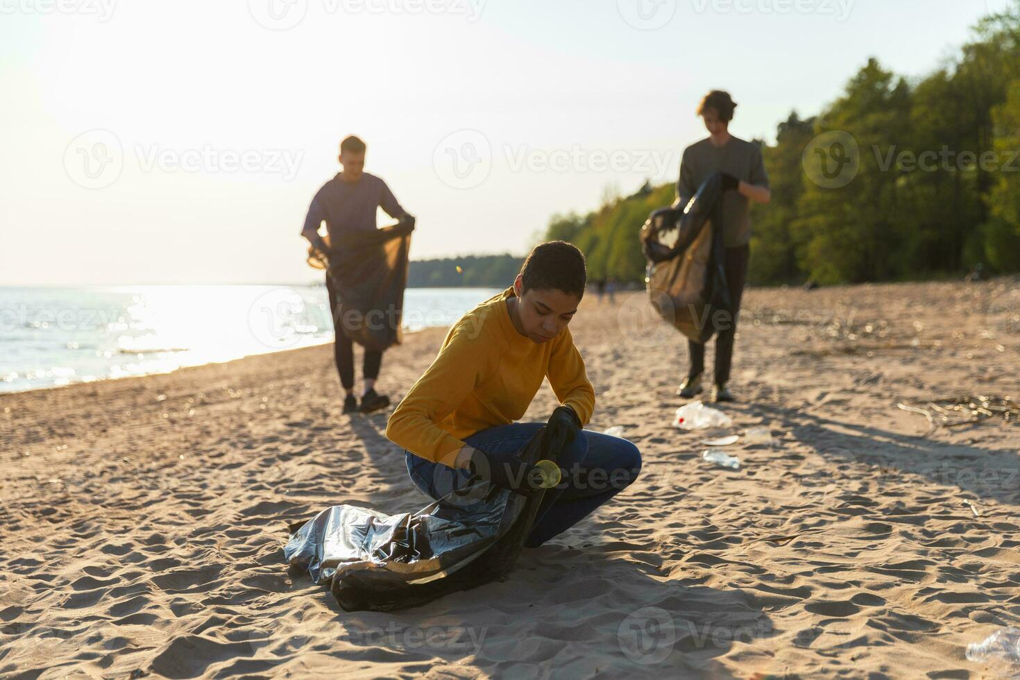 tierra día. voluntarios activistas recoge basura limpieza de playa costero zona. mujer y mans pone el plastico basura en basura bolso en Oceano costa. ambiental conservación costero zona limpieza. foto