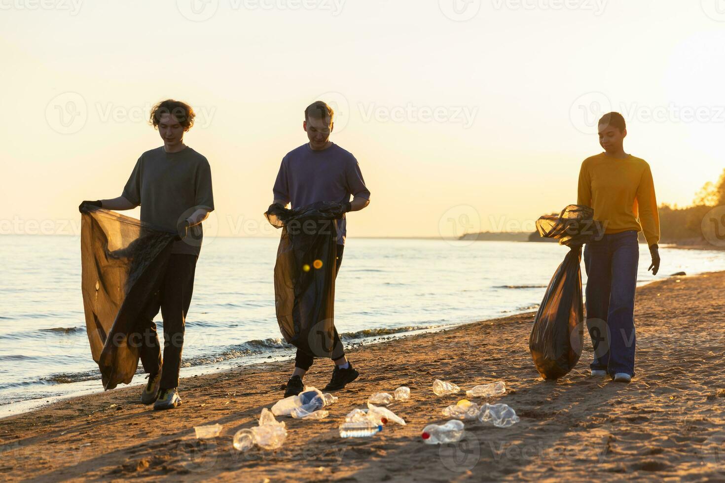 Earth day. Volunteers activists team collects garbage cleaning of beach coastal zone. Woman mans with trash in garbage bag on ocean shore. Environmental conservation coastal zone cleaning. photo