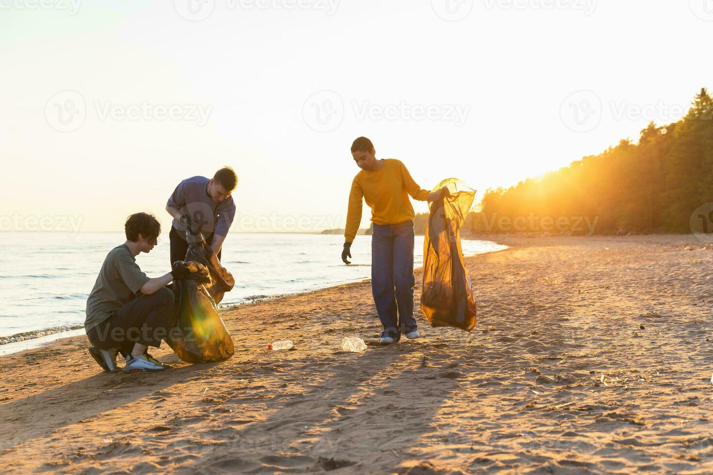 tierra día. voluntarios activistas recoge basura limpieza de playa costero zona. mujer y mans pone el plastico basura en basura bolso en Oceano costa. ambiental conservación costero zona limpieza. foto