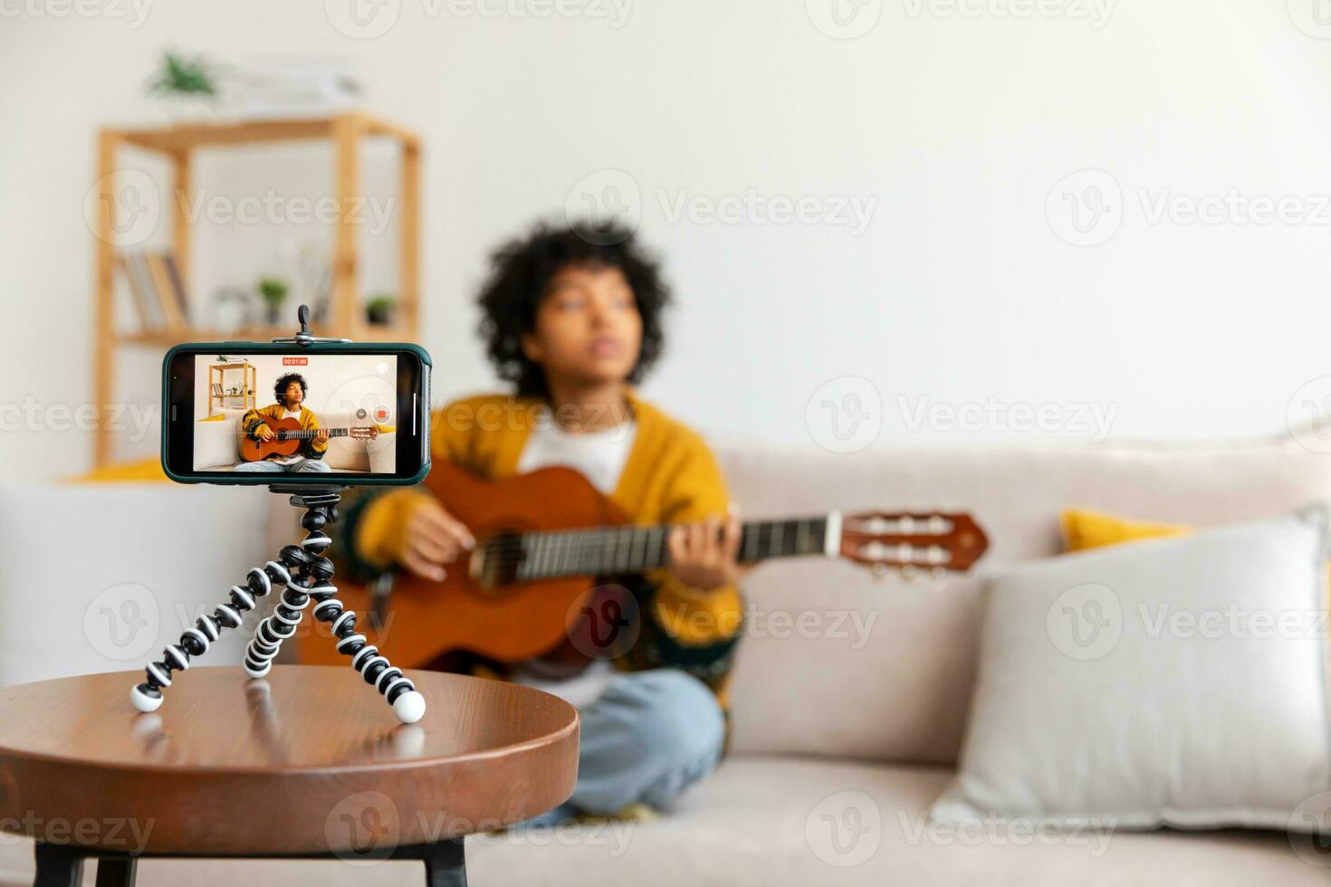 Blogger guitarist. African american girl blogger playing guitar talking to webcam recording vlog. Social media influencer woman streaming at home indoors. Music content creator broadcast tutorial. photo