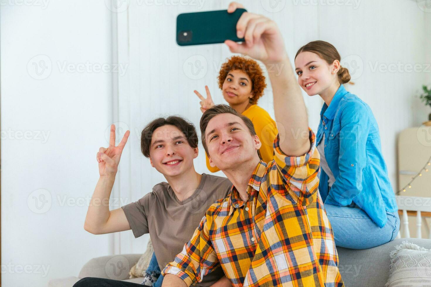 Cheers Funky mood. Happy group of friends make selfie. Man taking photo of friends at party. Group of multiracial young people taking photo on phone. Young people enjoy their company smile have fun.