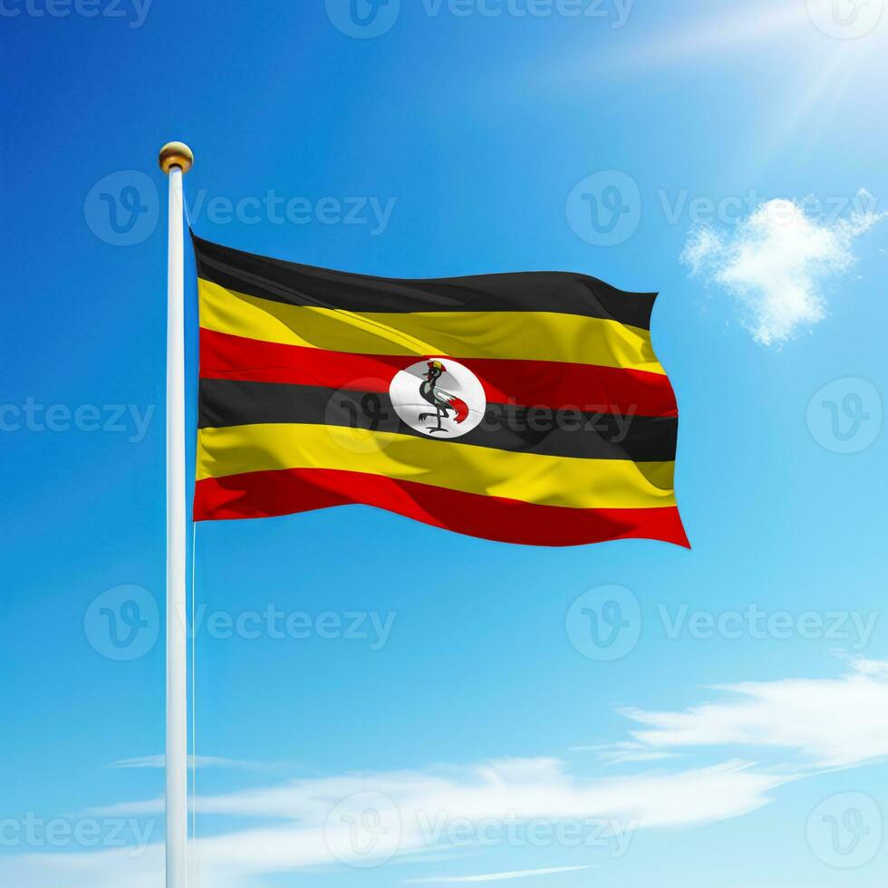 ondulación bandera de Uganda en asta de bandera con cielo antecedentes. foto