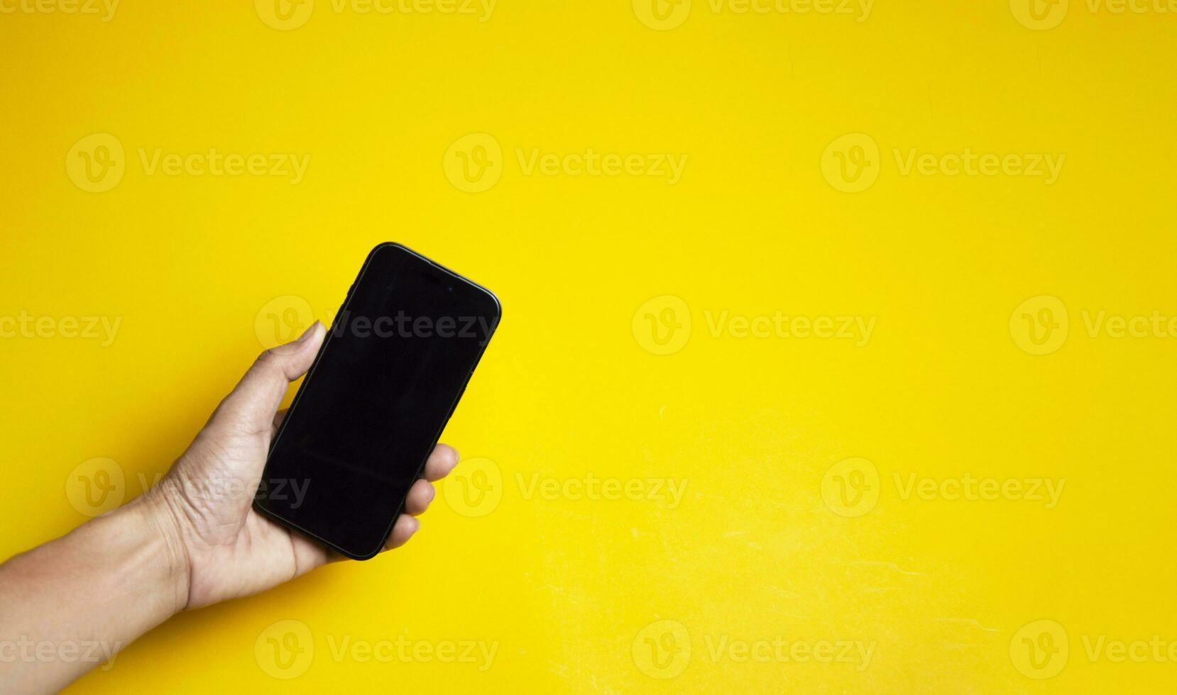 mano participación un teléfono inteligente en un amarillo antecedentes foto