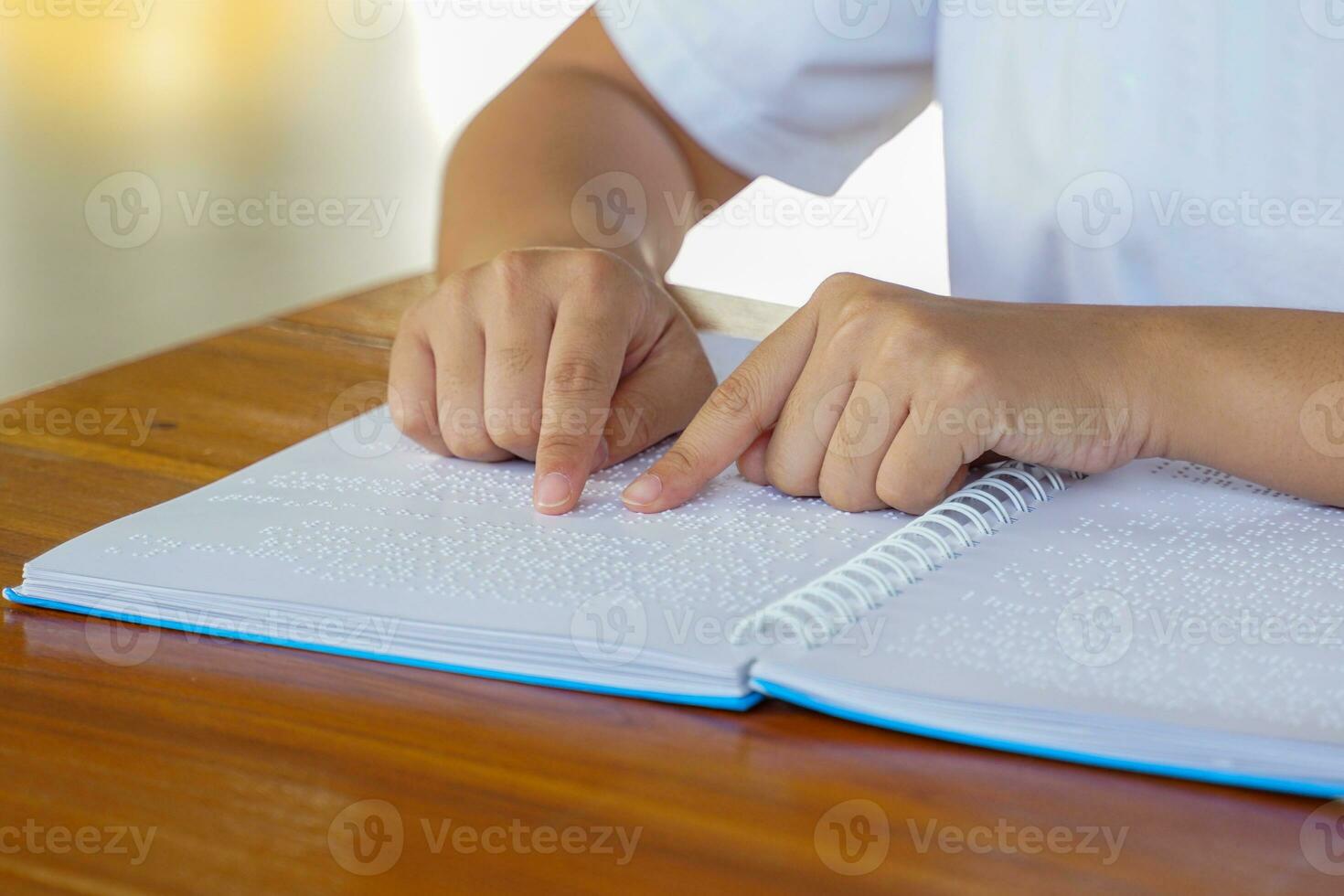 Visually impaired person reads with his fingers a book written in braille It is written for those who are visually impaired or blind. It is a special code generated from 6 dots in the box. photo