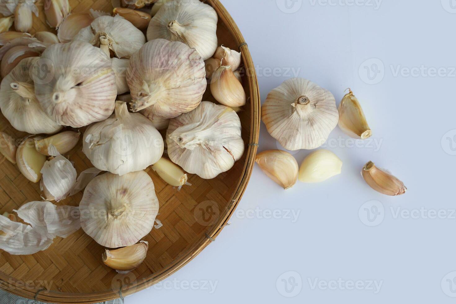 Garlic in a bamboo basket on a white background It is a medicinal plant in Thai kitchens used as an ingredient in food. It has a pungent odor and a spicy taste. It can be eaten both fresh and cooked. photo