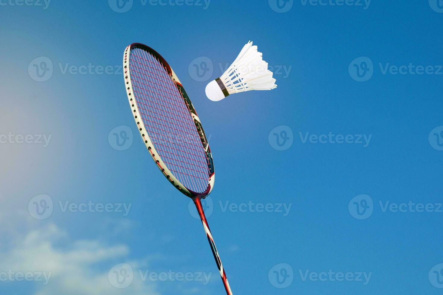 Badminton racket and white shuttlecock on cloudy sky background. Concept playing badminton outdoors. photo