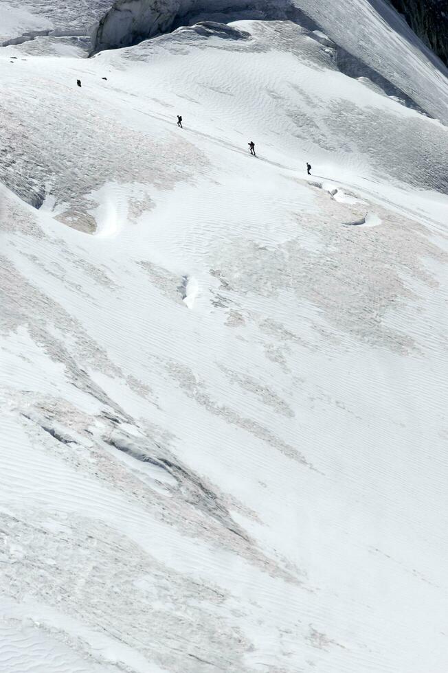 two people are hiking up a mountain with snow covered mountains photo