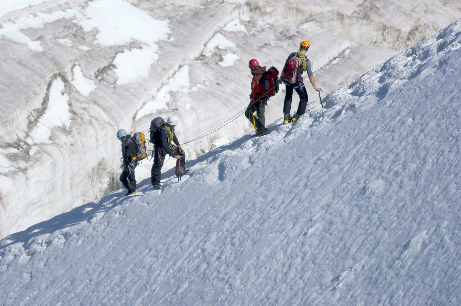 two people are hiking up a mountain with snow covered mountains photo