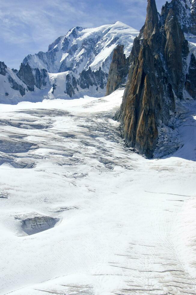 dos personas son excursionismo arriba un montaña con nieve cubierto montañas foto