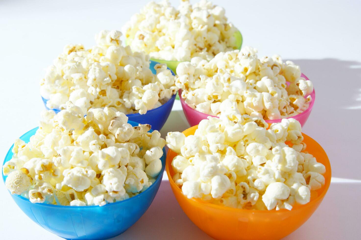 four colorful bowls of popcorn on a white surface photo