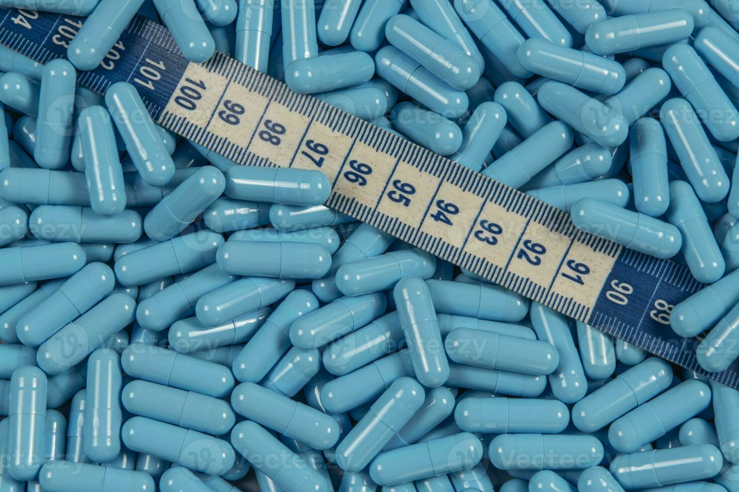 Blue weight loss pills and measuring tape symbolizing slimming photo