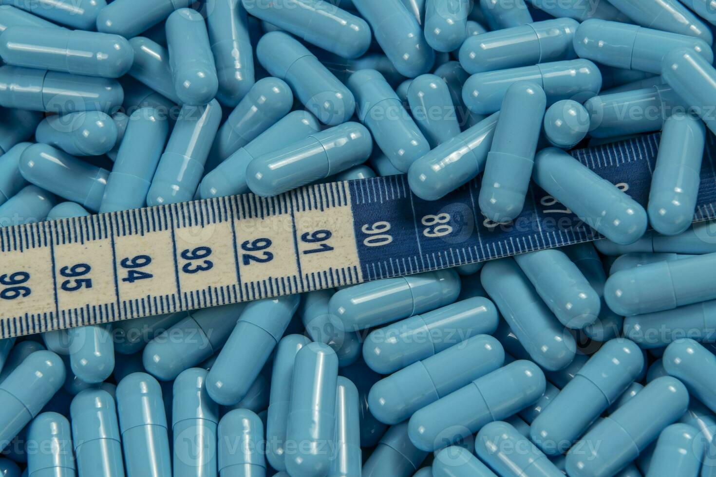 Blue weight loss pills and measuring tape symbolizing slimming photo