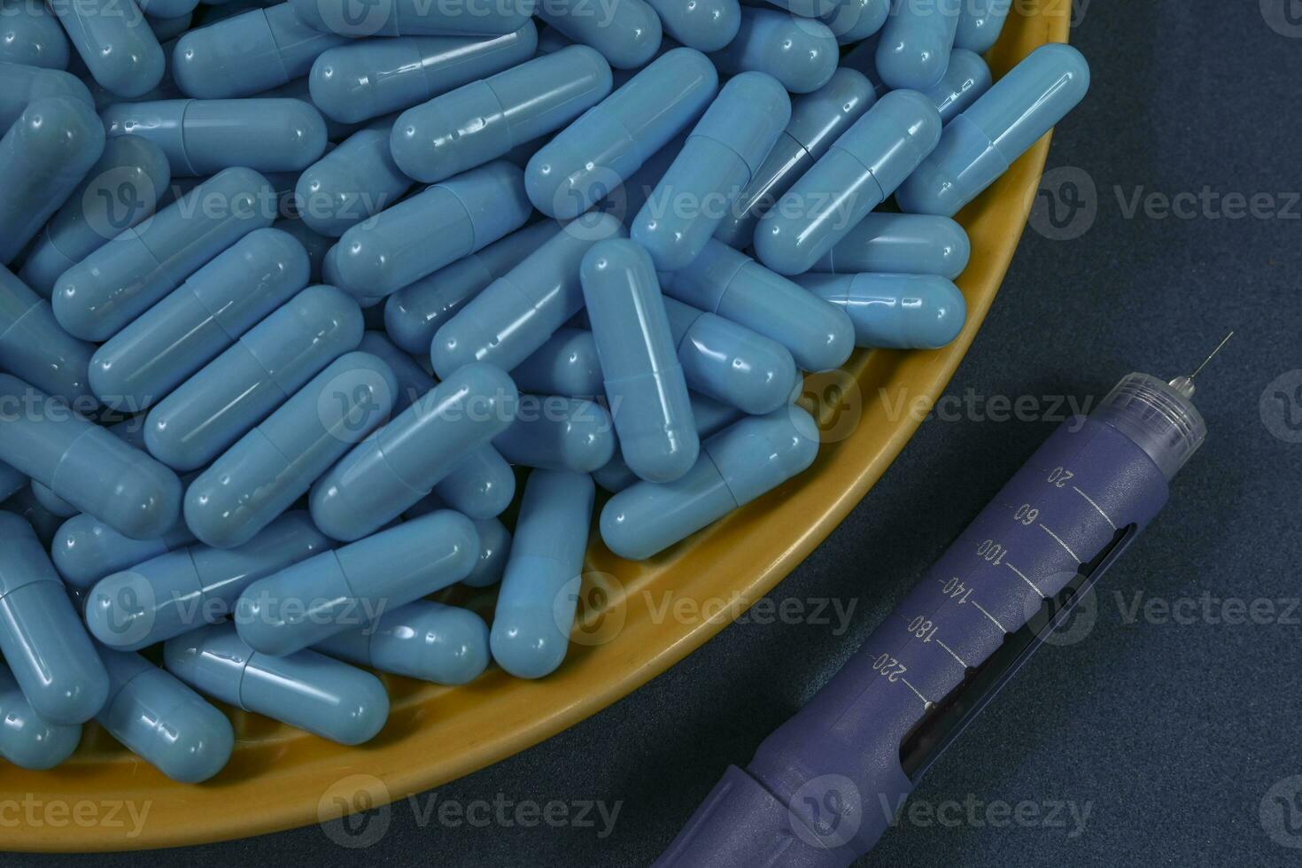 Yellow plate full of blue medicine capsules representing drug overdose photo