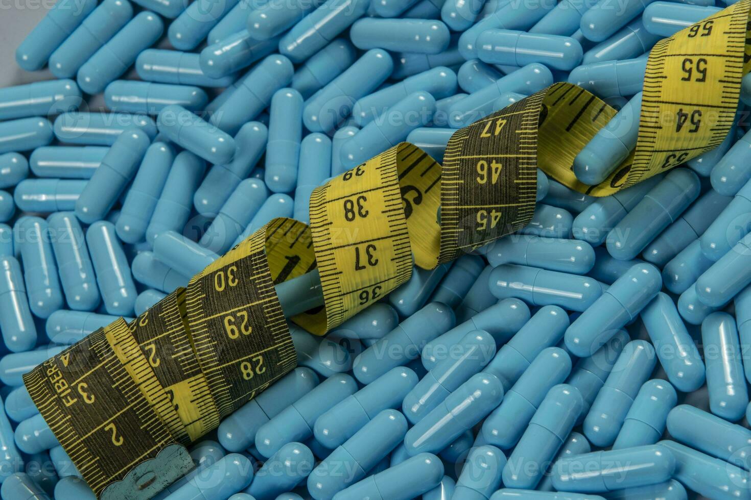Blue weight loss pills and measuring tape symbolizing slimming photo