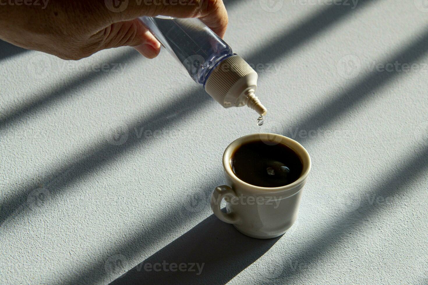 person sweetening coffee with liquid sweetener photo