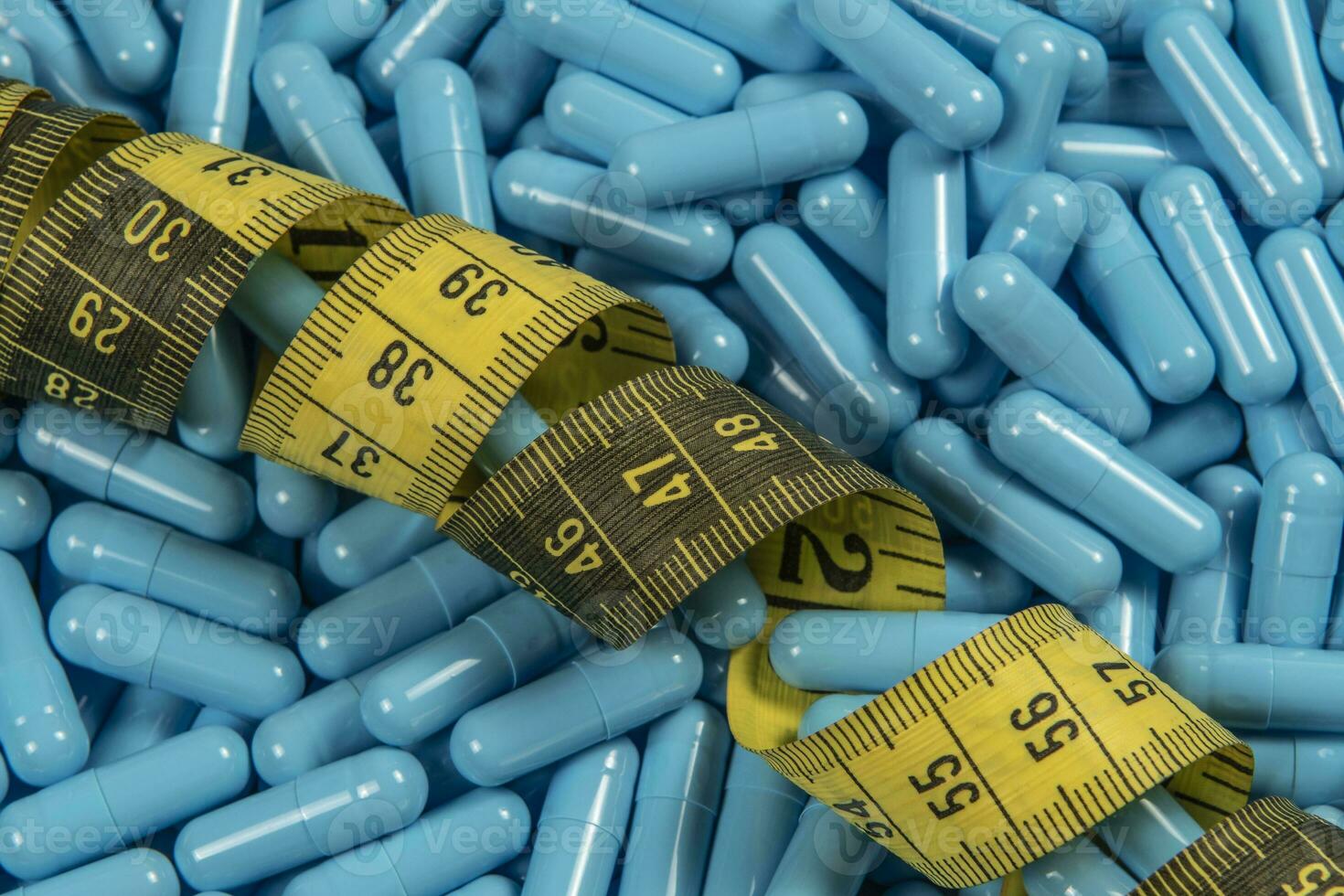 Blue weight loss pills and measuring tape symbolizing slimming photo