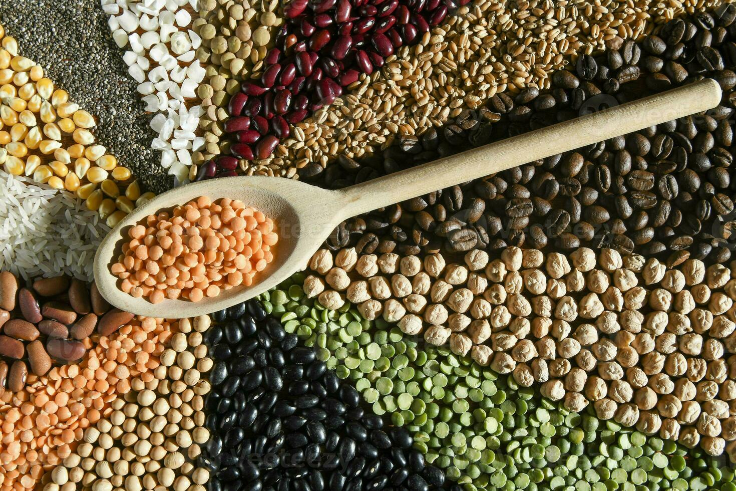 Wooden spoon with raw red lentils on various grain photo