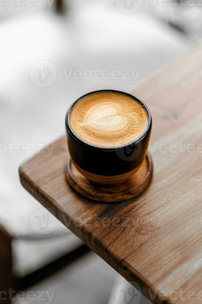 cerca arriba café taza con corazón forma latté Arte en madera lengüeta foto