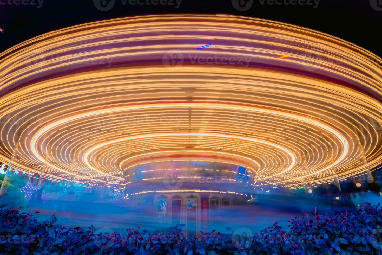 un noche escena de hilado alegre Vamos redondo carrusel en disneylandia bajo obturador velocidad. borroso foto