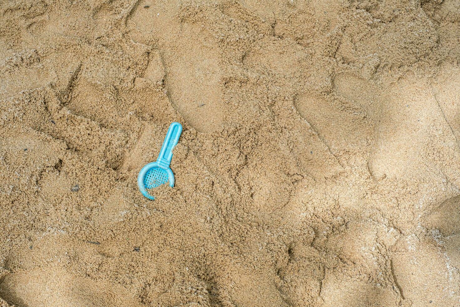 Flat lay of a beach filter spoon toy on the sandy surface of an outdoor playground. photo