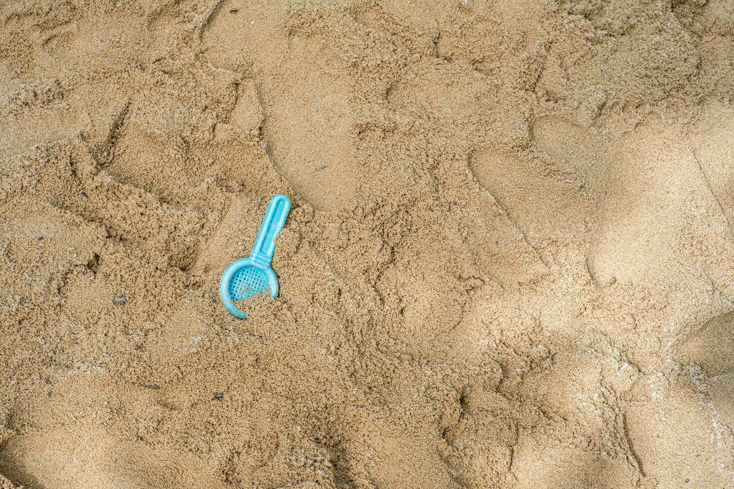 plano laico de un playa filtrar cuchara juguete en el arenoso superficie de un al aire libre patio de juegos. foto