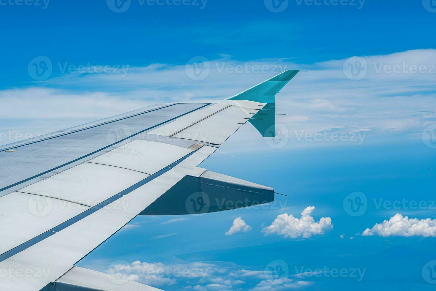 Clear blue sky with fluffy ornamental cumulus clouds, panoramic view from an airplane, wing close-up. Dreamlike cloudscape. Travel, tourism, vacations, weekend, freedom, peace, hope, heaven concepts photo