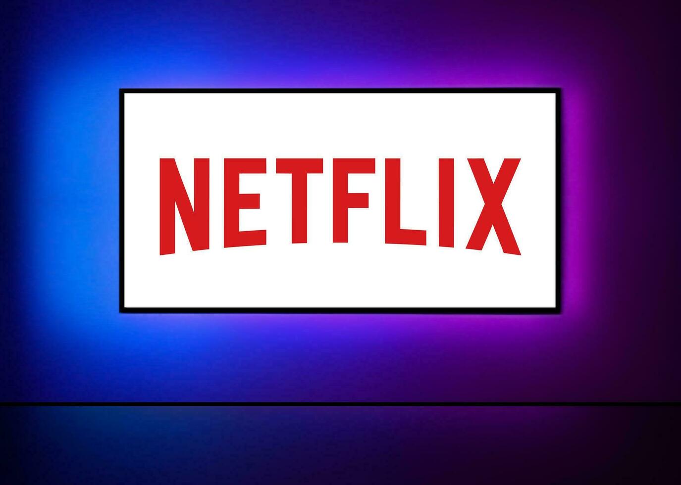 Netflix logo on the big TV screen with neon colorful background on wall. Netflix is an American entertainment company founded by Hastings and Randolph. Vector illustration
