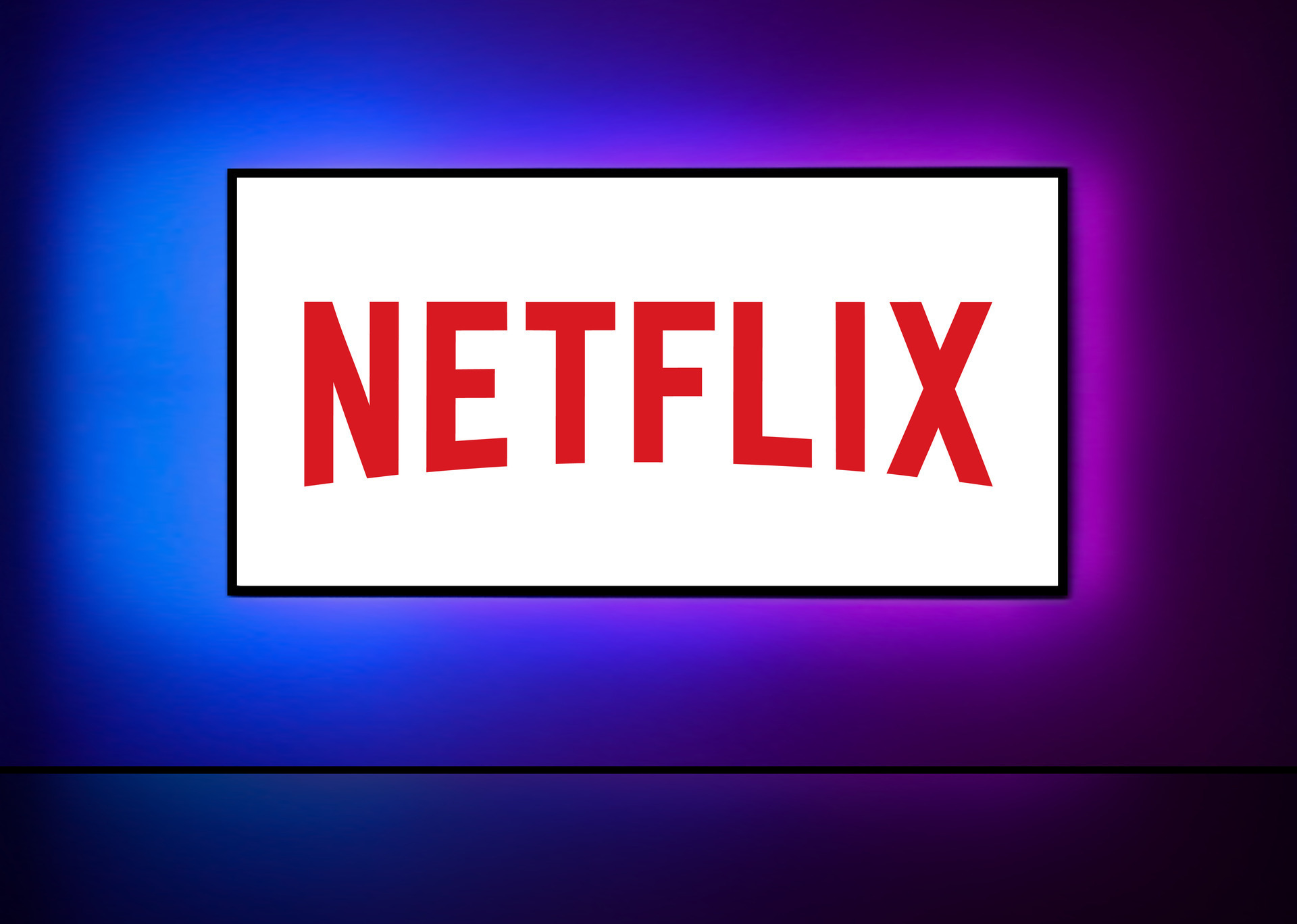 Netflix logo on the big TV screen with neon colorful background on wall