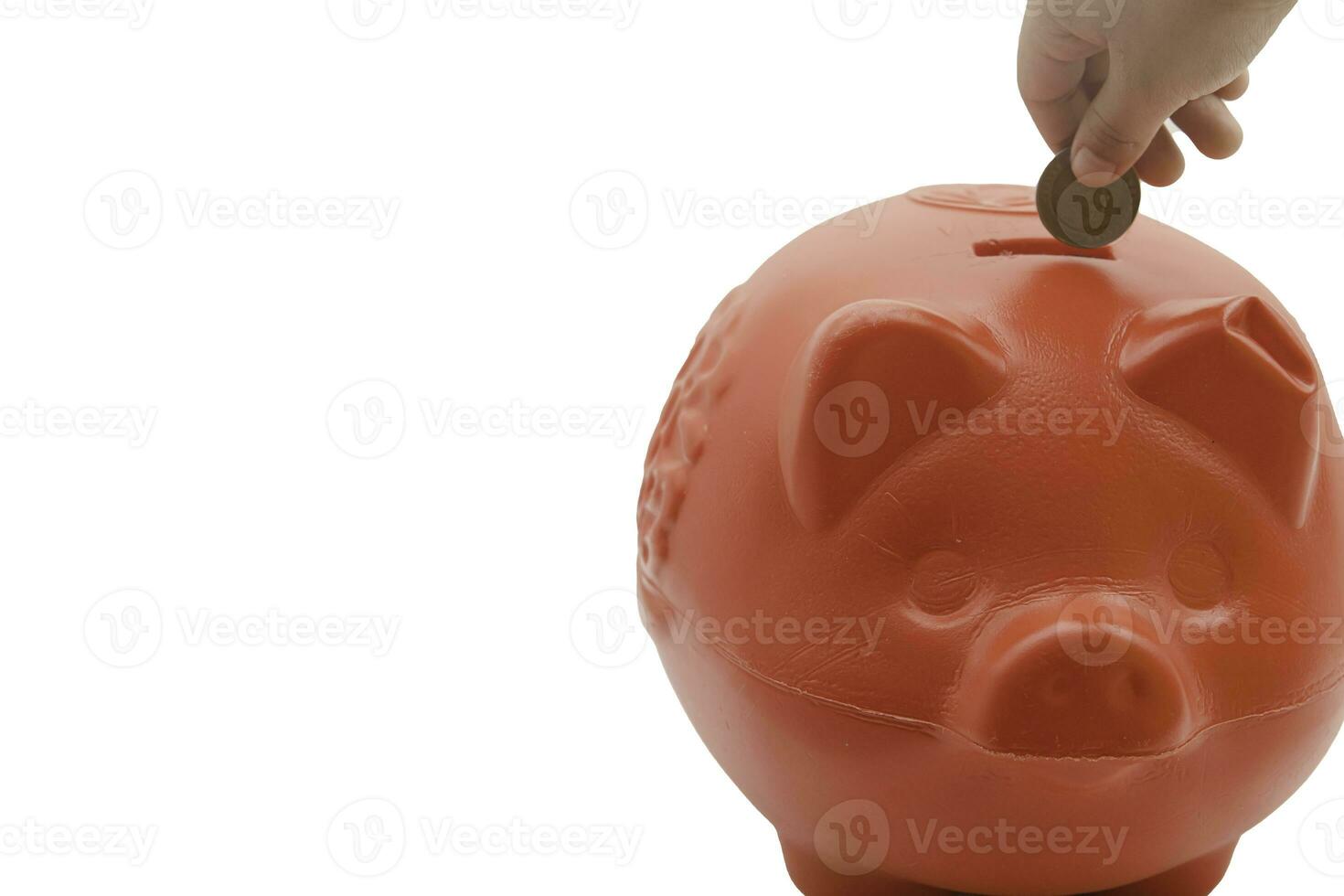 child hand putting coin into piggy bank from the top view isolated on white background, saving concept. Copy space for your text photo