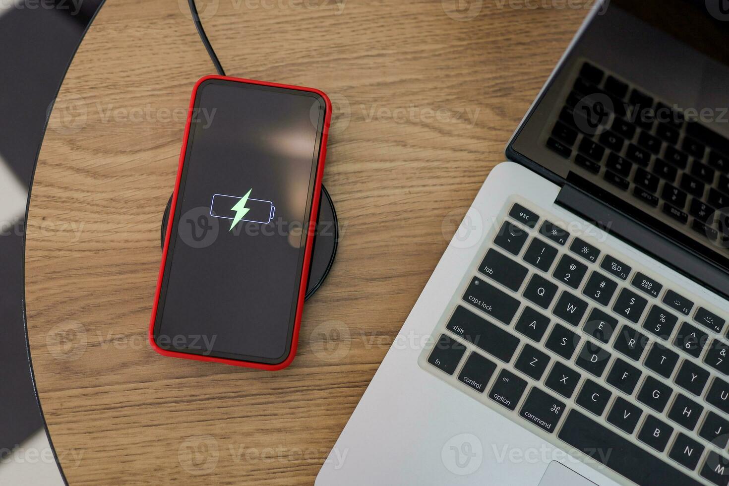 Charging mobile phone battery with wireless device in the table. Smartphone charging on a charging pad. Mobile phone near wireless charger. photo