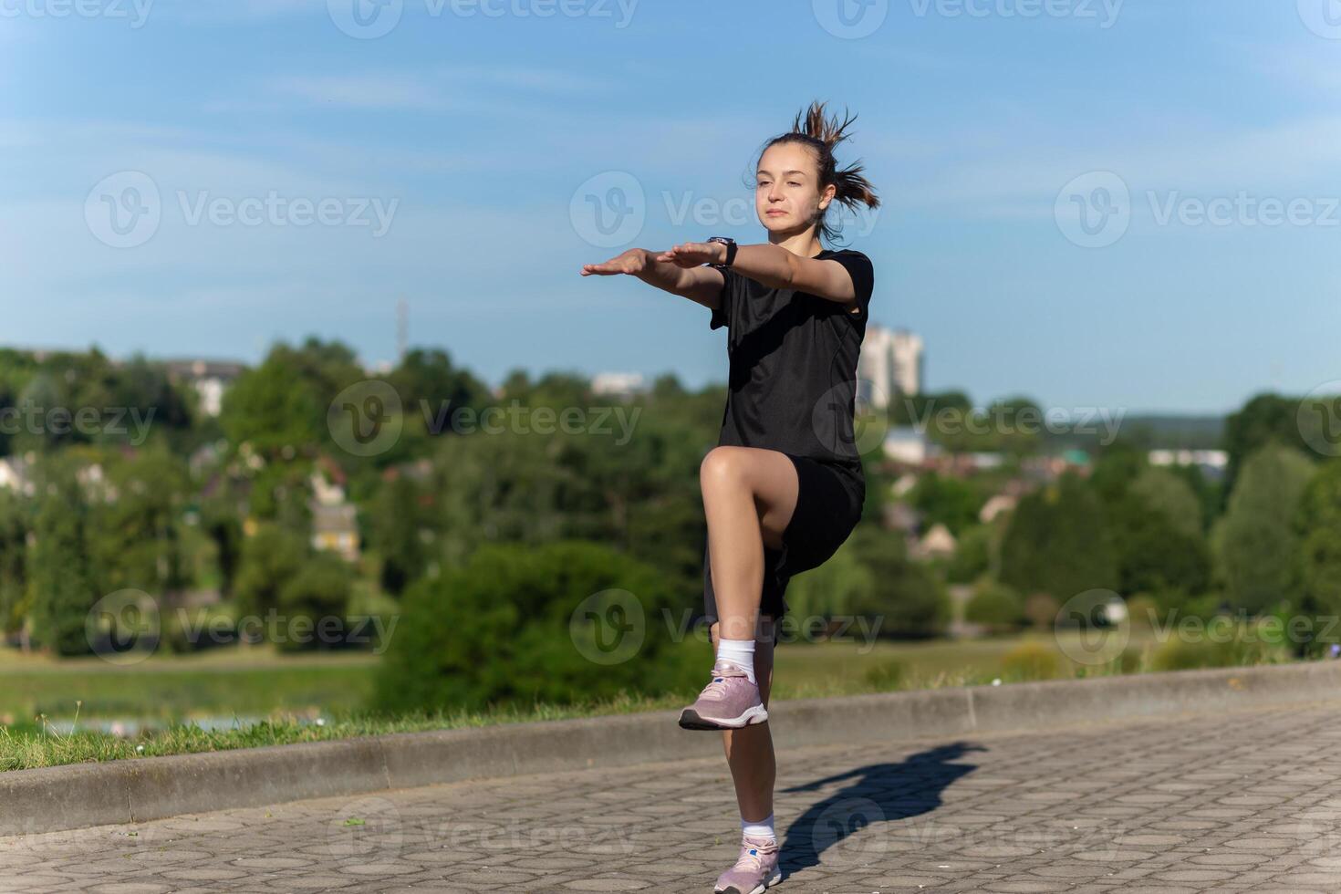 joven, ajuste y deportivo niña en negro ropa extensión después el rutina de ejercicio en el urbano ciudad parque. foto