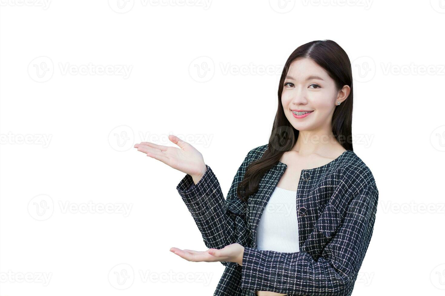 Asian professional working business woman who wears black suit with braces on teeth is pointing hand to present something while isolated on white background. photo