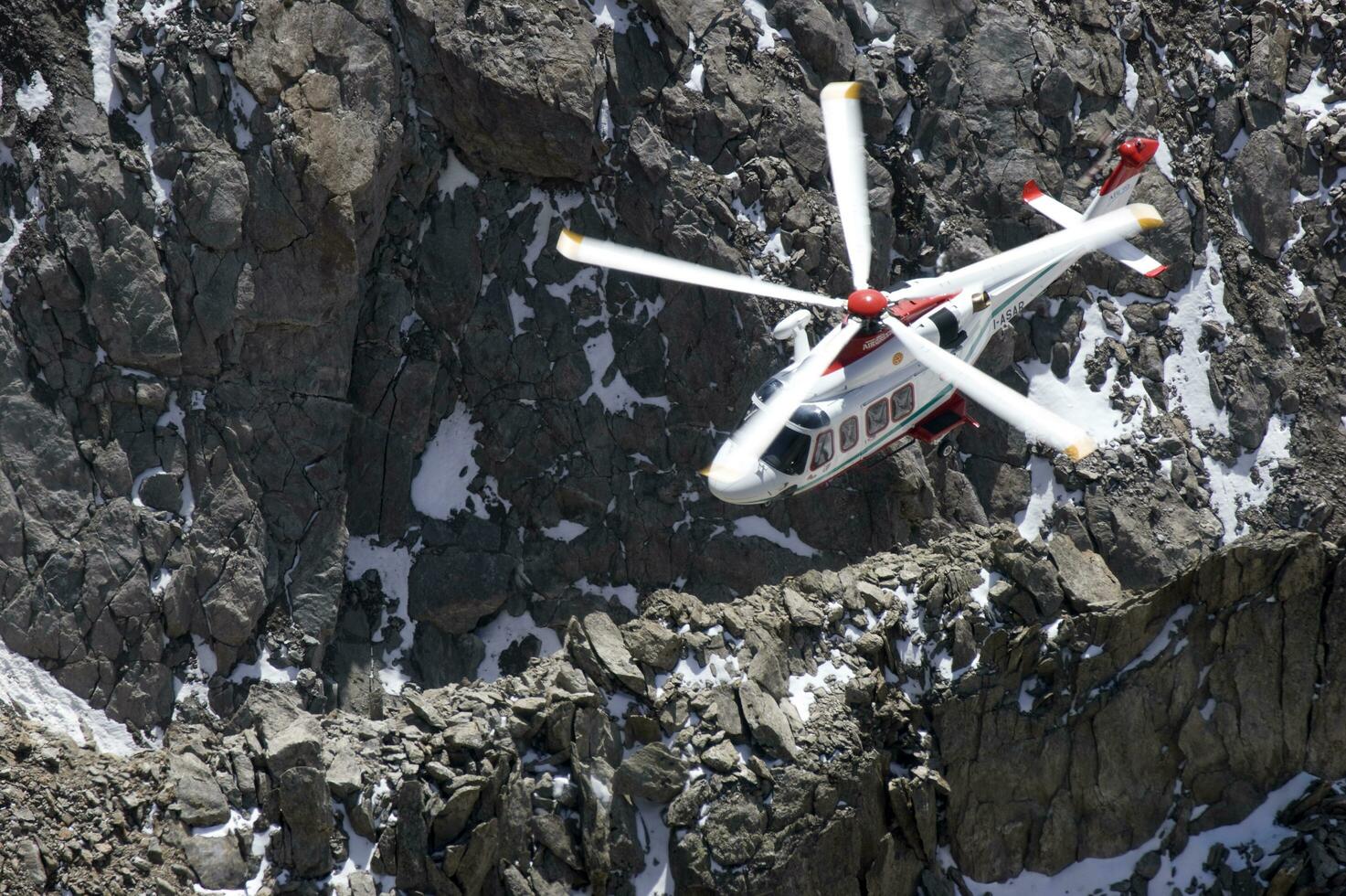 a helicopter is flying over a rocky mountain photo