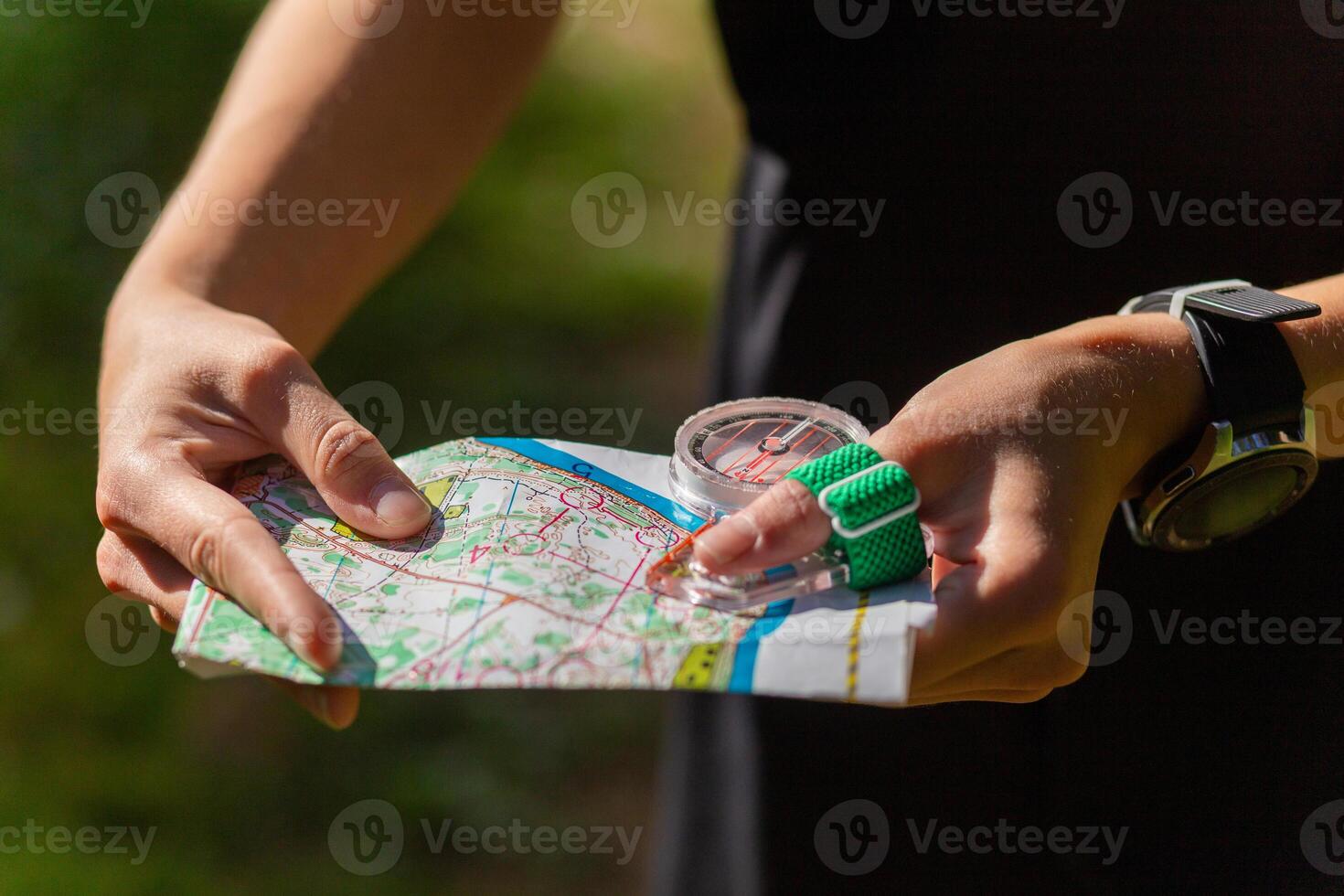 Woman holding a map and the compass during orienteering competitions. photo