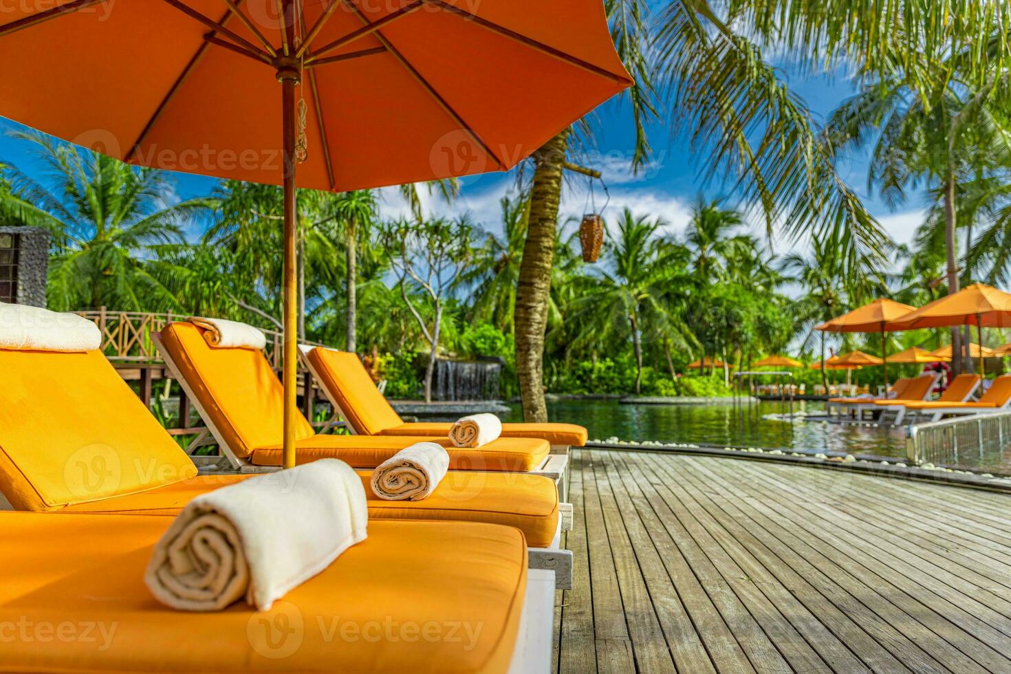 Outdoor tourism landscape. Luxurious beach resort with swimming pool and beach chairs or loungers under umbrellas with palm trees and blue sky. Summer travel and vacation background concept photo