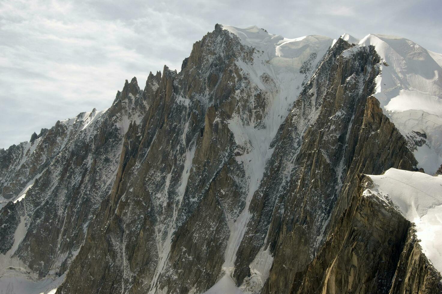 two people are hiking up a mountain with snow covered mountains photo
