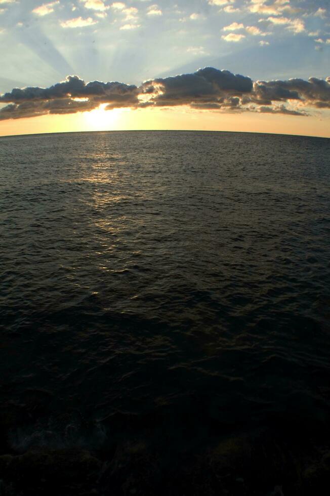 a boat is sailing across the ocean at sunset photo