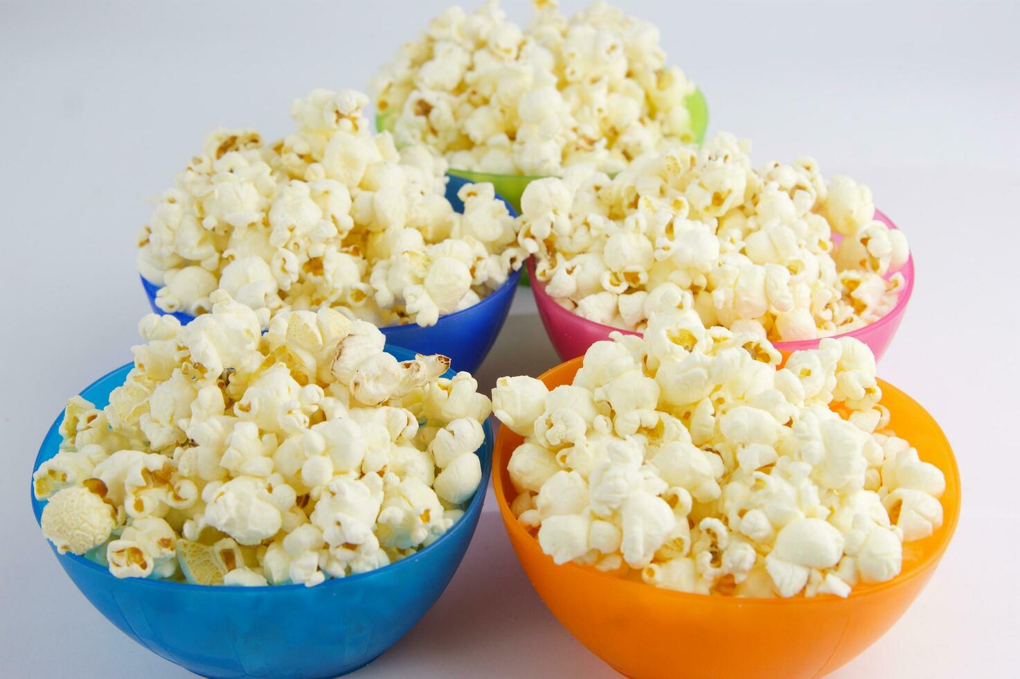 four colorful bowls of popcorn on a white surface photo