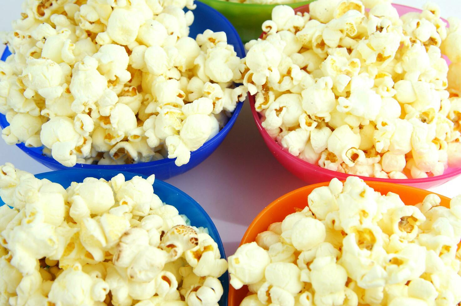 four colorful bowls of popcorn on a white surface photo