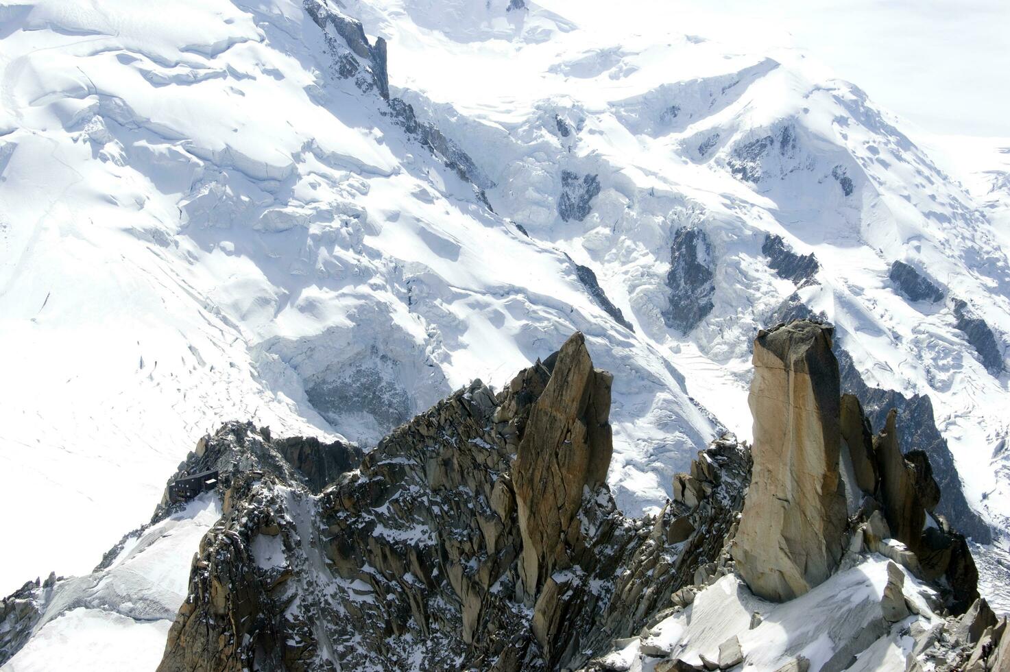 dos personas son excursionismo arriba un montaña con nieve cubierto montañas foto