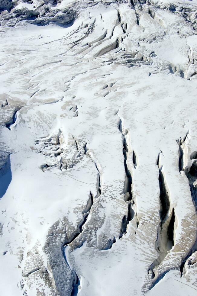 dos personas son excursionismo arriba un montaña con nieve cubierto montañas foto