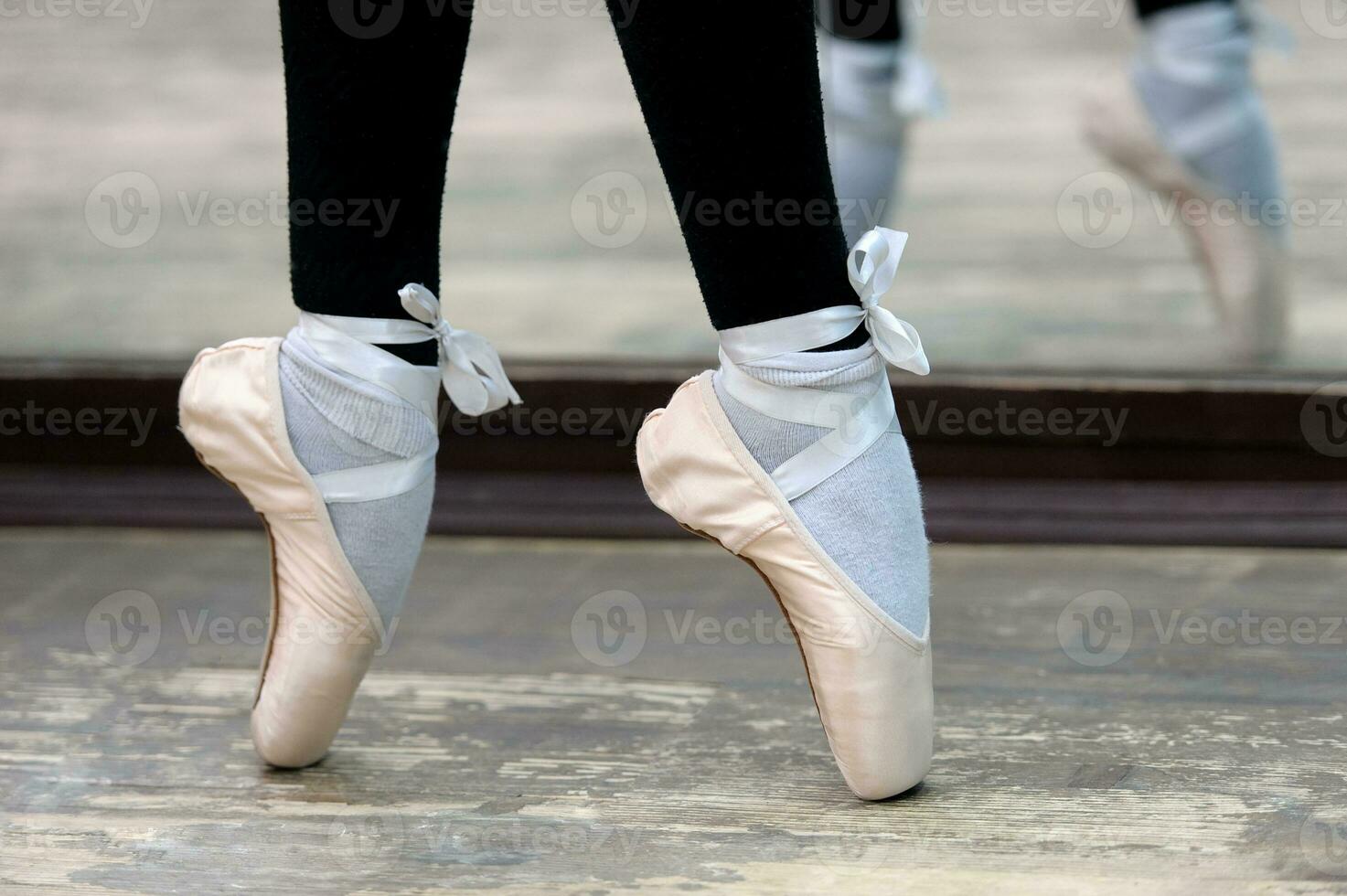 Close up view to ballerinas legs in pointes on wooden floor photo
