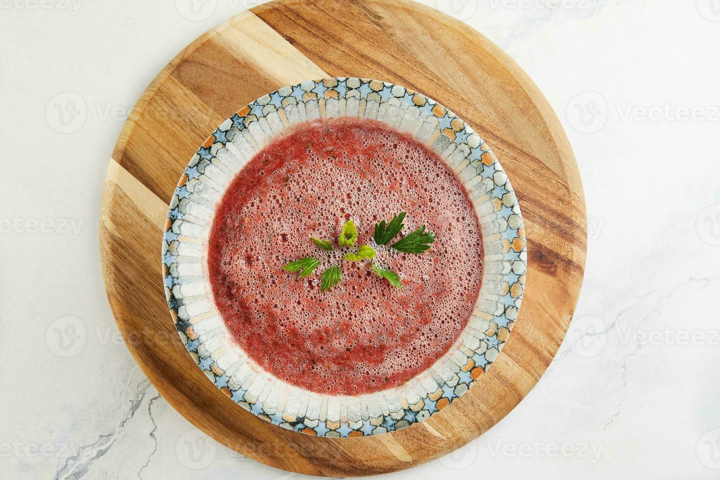 Gazpacho soup with herbs in a deep plate on a wooden board photo