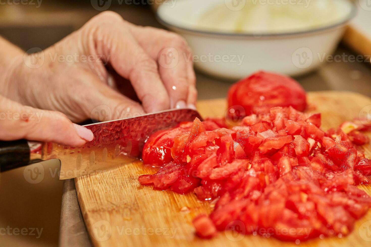 Chef cuts the tomatoes into small cubes for cooking photo