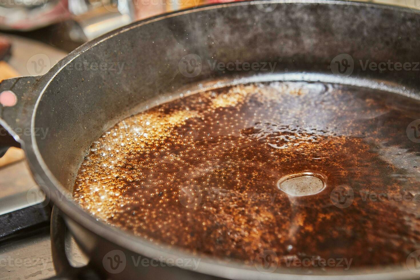 Caramelized syrup in frying pan on gas stove photo