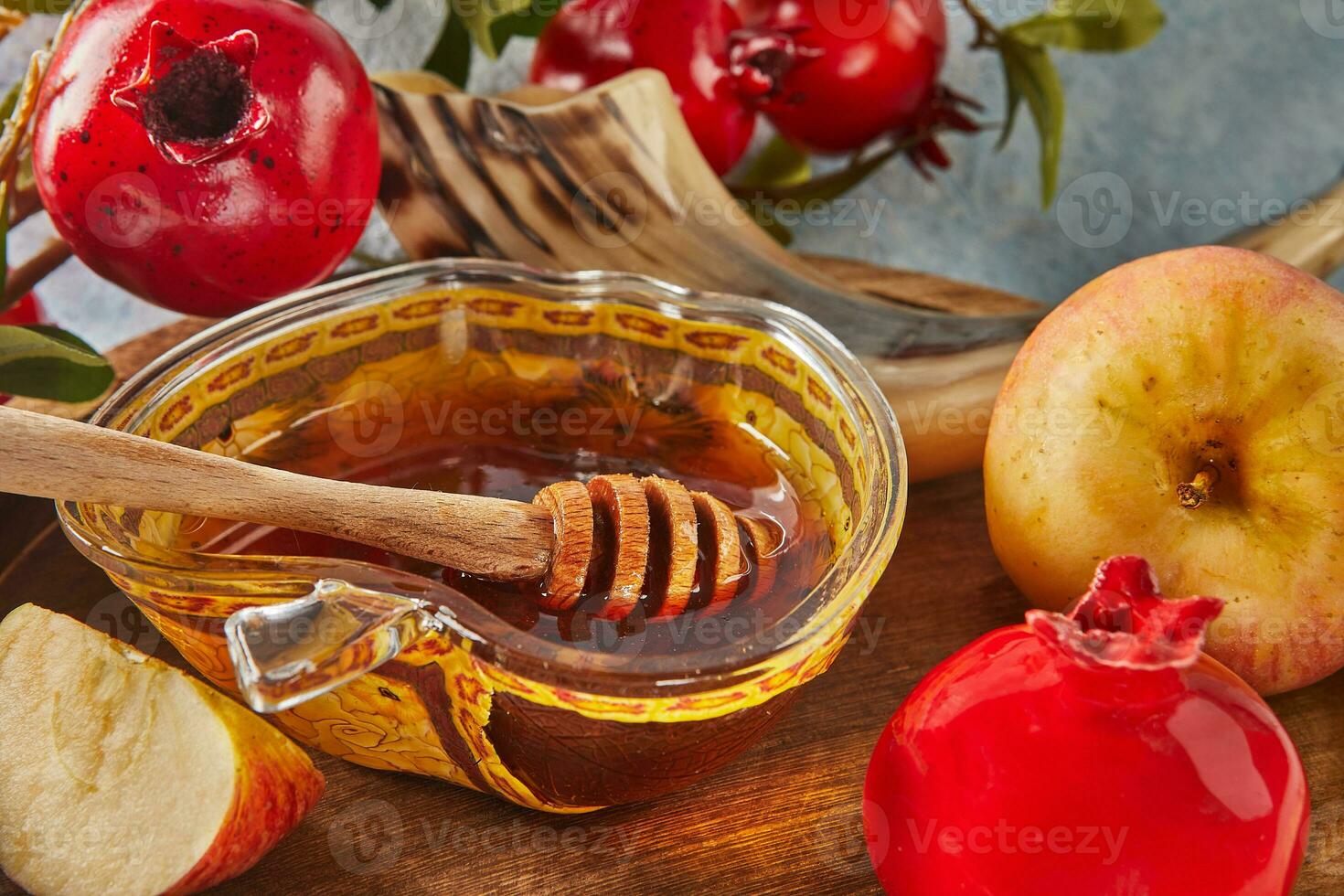 Rosh hashanah - jewish new year holiday concept. Bowl in the shape of an apple with honey, apples, pomegranates, shofar on a blue background photo